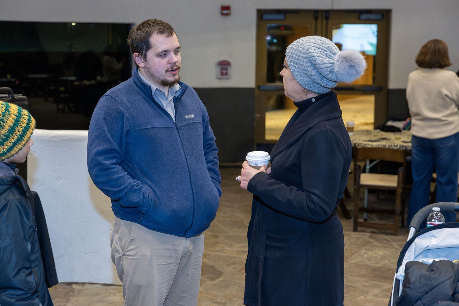 People mingling at indoor networking event with casual winter attire.