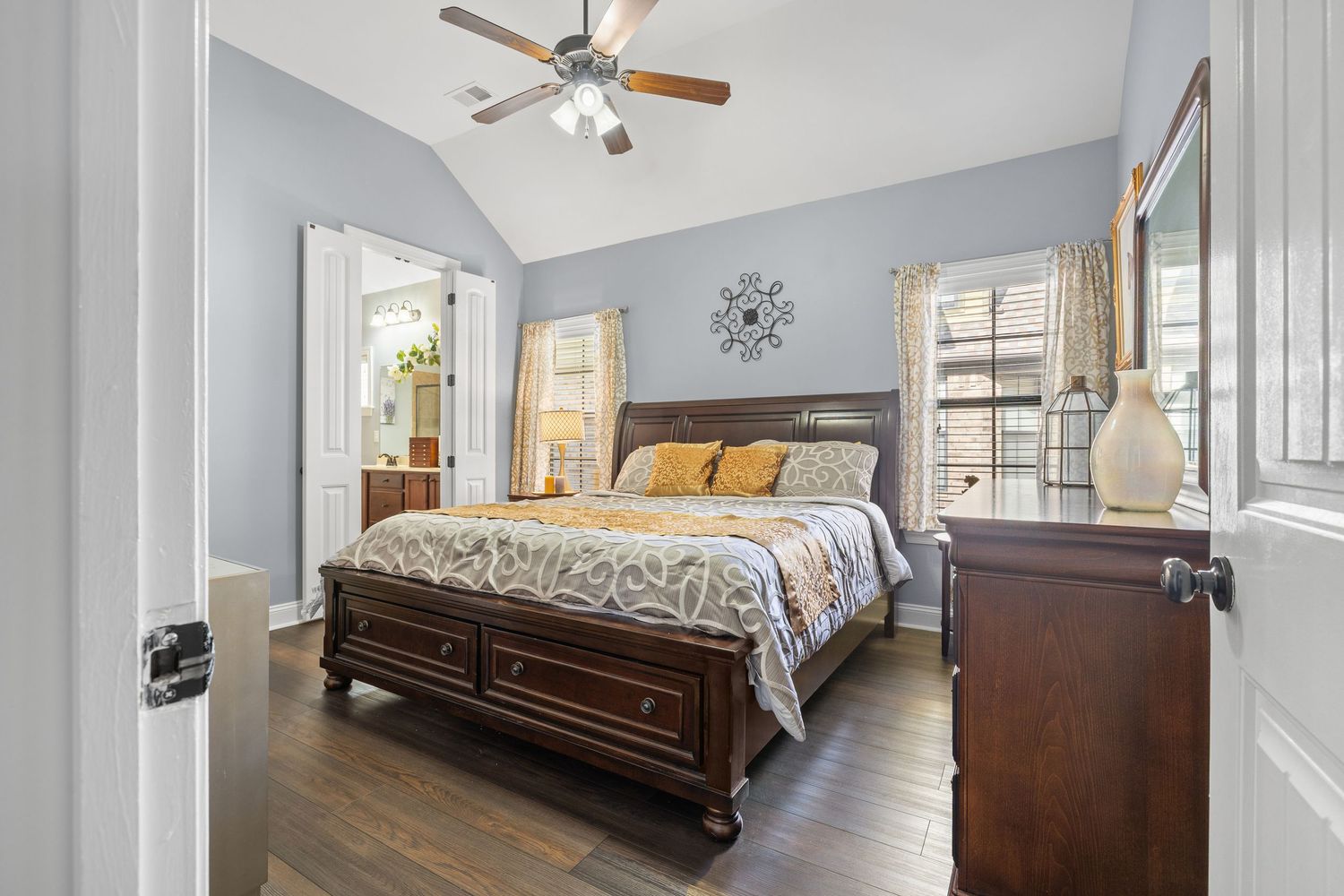 Modern bedroom with dark wood furniture, ceiling fan, and gray walls showcases clean lines and natural lighting.
