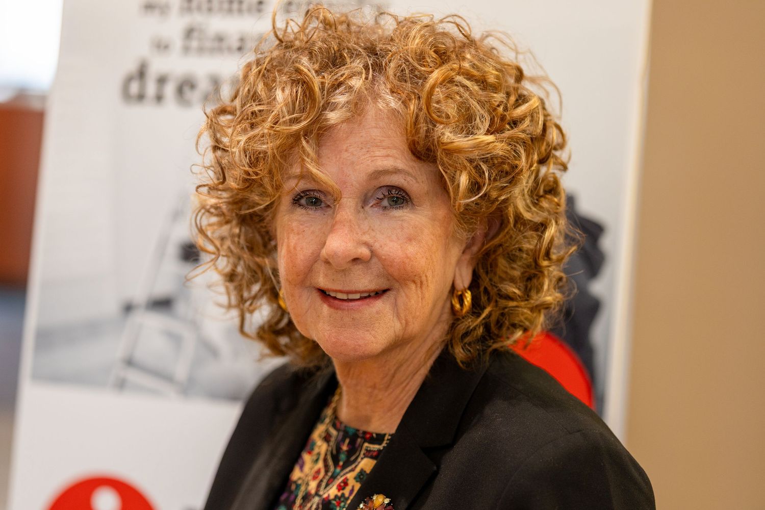 Side view portrait of woman with curly auburn hair in professional setting.