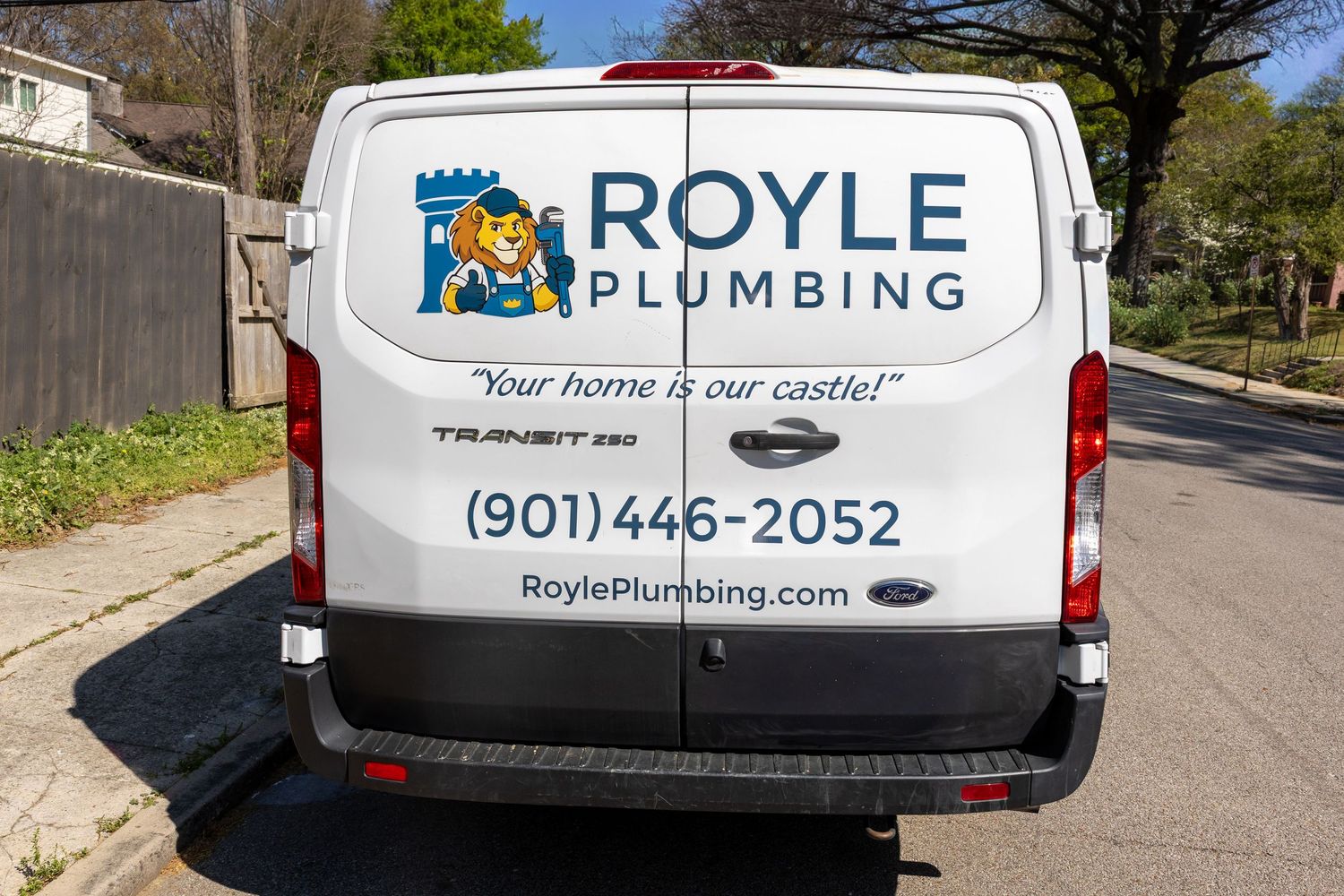 Royle Plumbing white Ford Transit van with phone number 901-446-2052 and website RoylePlumbing.com parked on street.