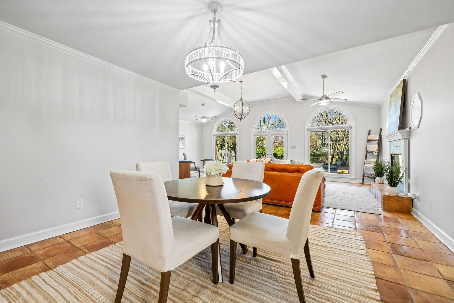 Modern open concept dining room with white walls, hardwood floors, and orange accent chairs around a white dining table.