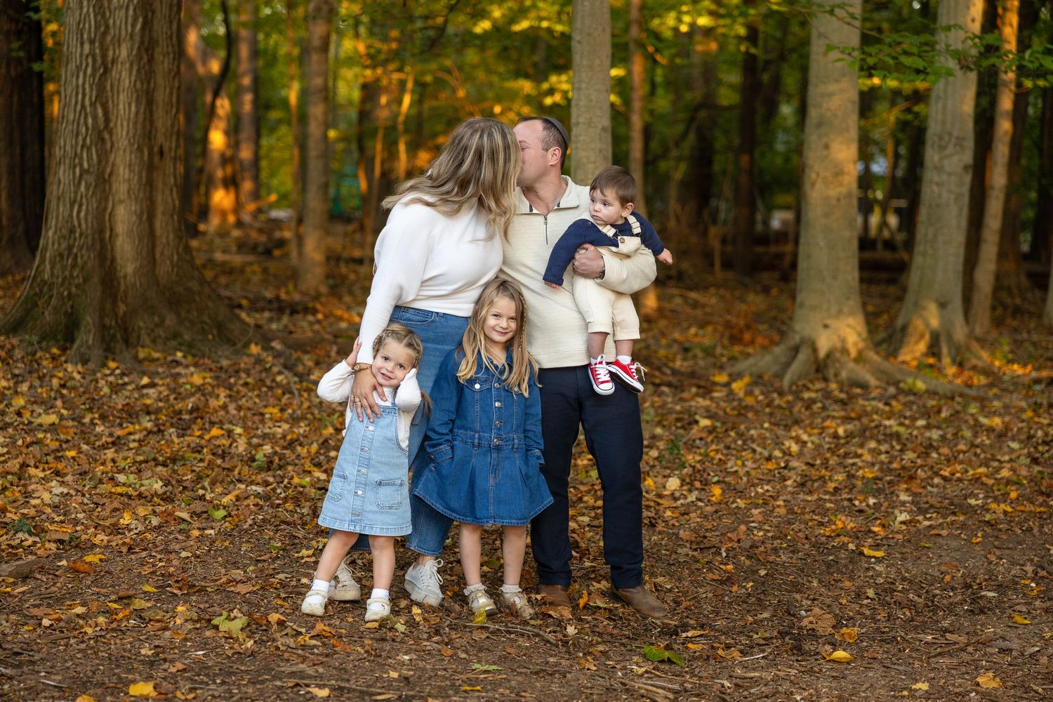 Family photography session in wooded area with fall foliage.
