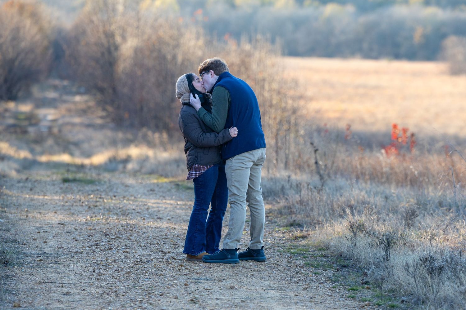 Candid proposal moment captured in a rustic outdoor setting at sunset.