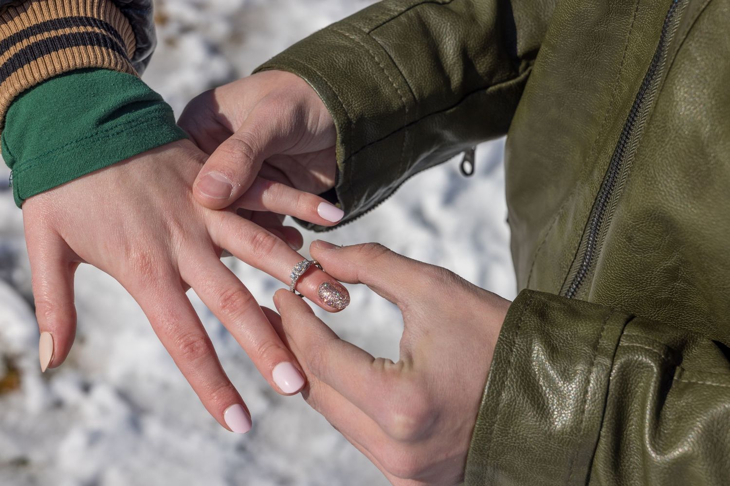 Close-up shot of hands exchanging rings in the snow.