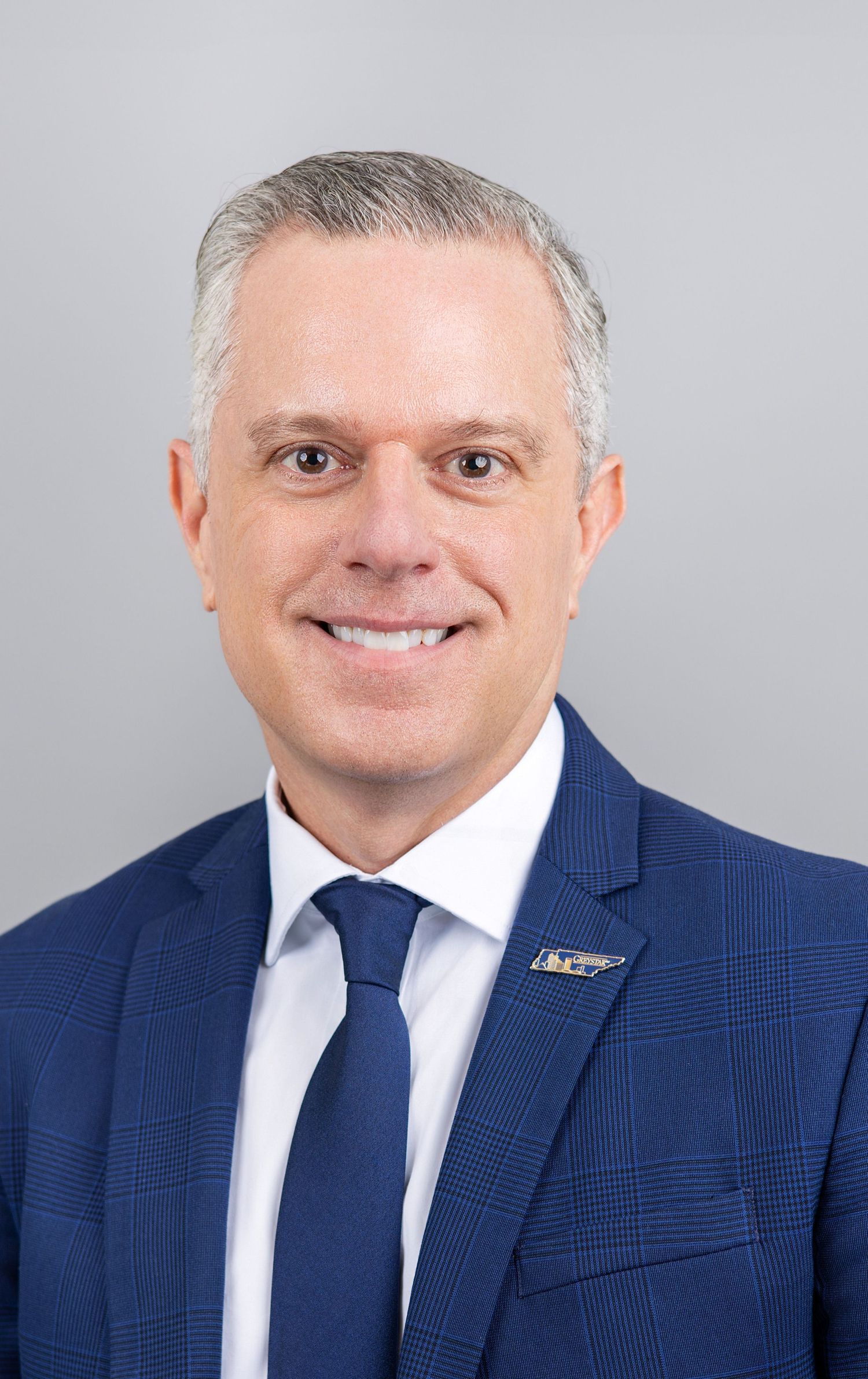 Professional headshot series in navy checkered suit against grey background.