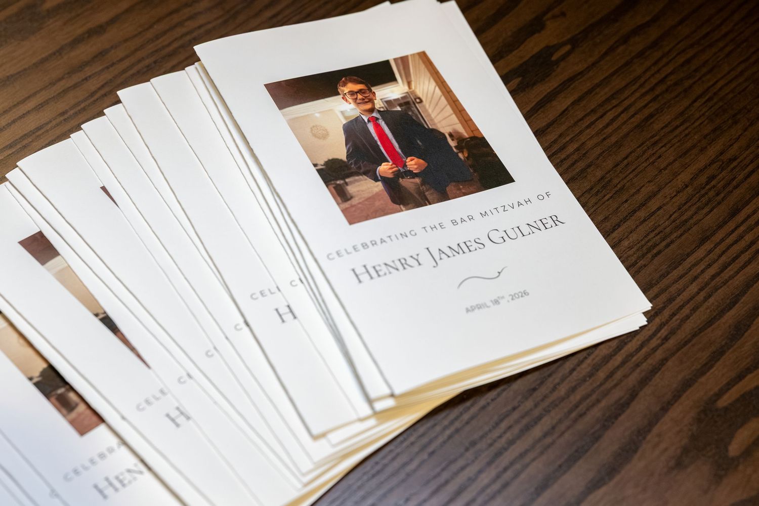 Memorial programs for Henry James Gulner celebration of life service stacked on a wooden table.