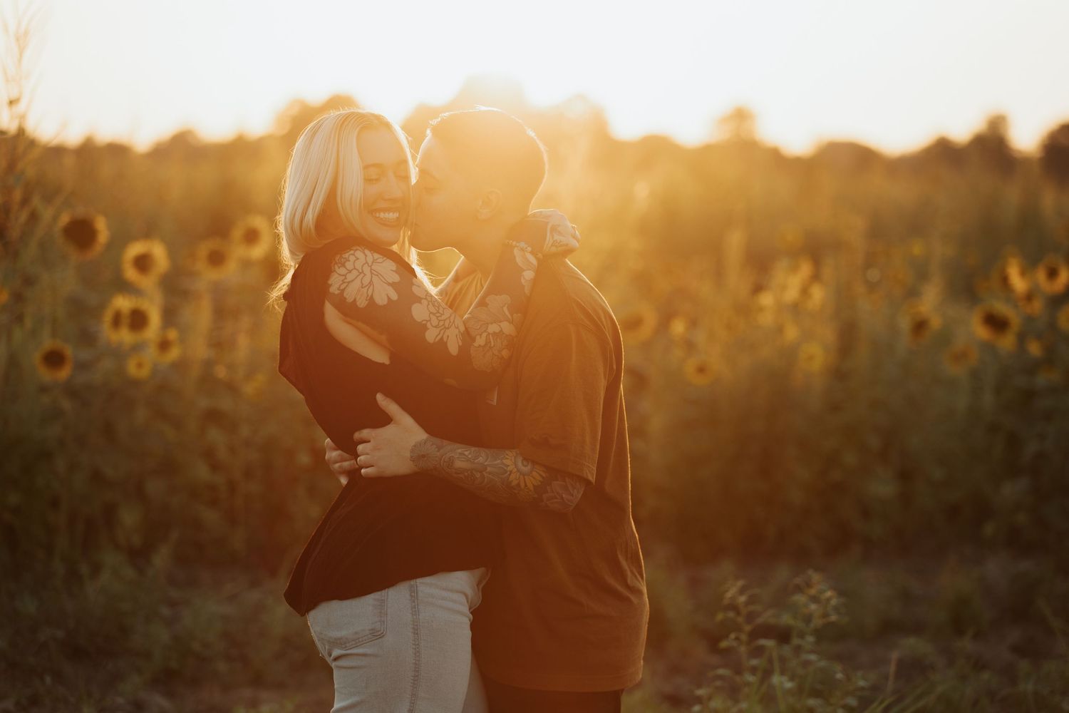 Romantic silhouette of a couple embracing in a sunlit sunflower field during golden hour.