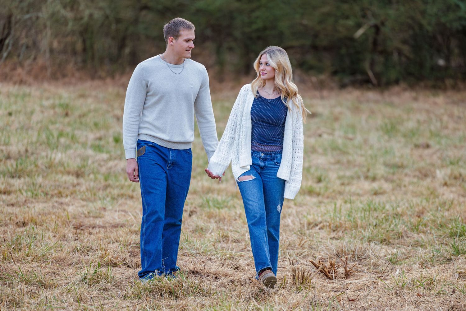 Two people in coordinated outfits sharing a romantic moment in a rustic outdoor setting.