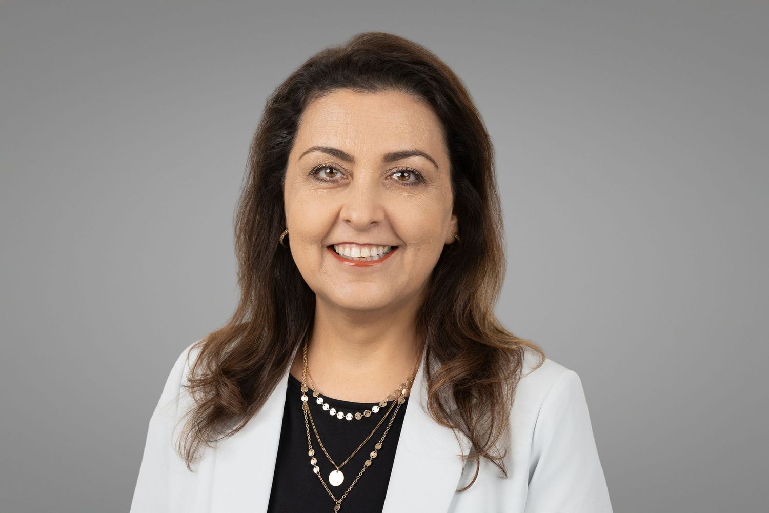 Professional headshots of woman in white blazer against gray studio background.
