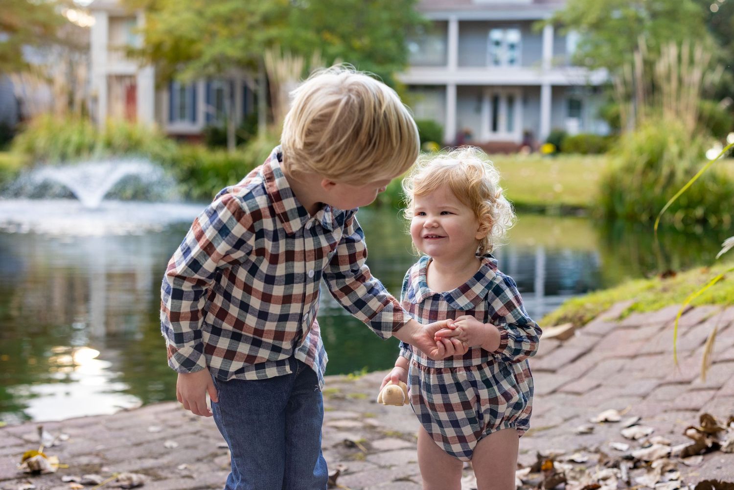 Children exploring near water's edge on stone pathway.