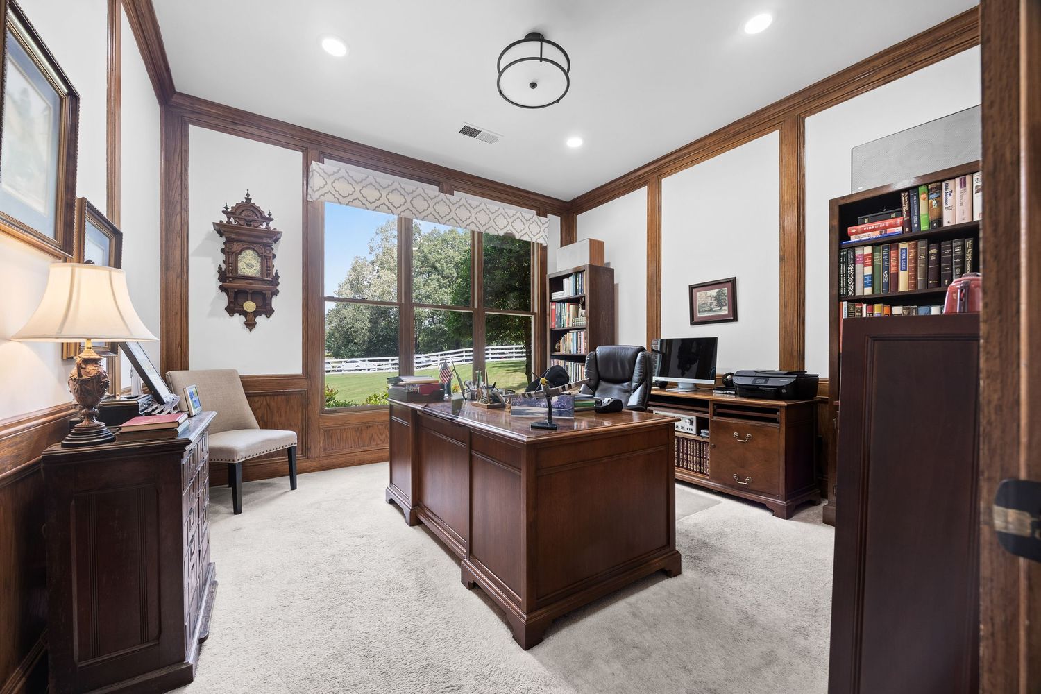 Modern home office space with dark wood trim and built-in cabinetry showcases a wrap-around desk setup and recessed lighting.
