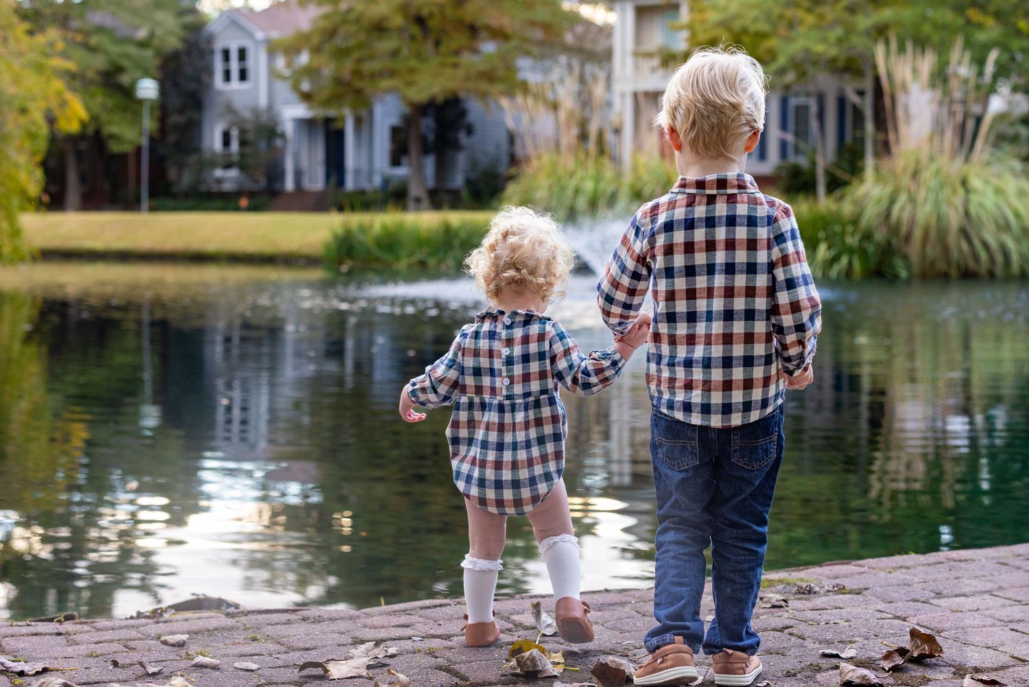 People standing by a serene pond on an autumn afternoon.