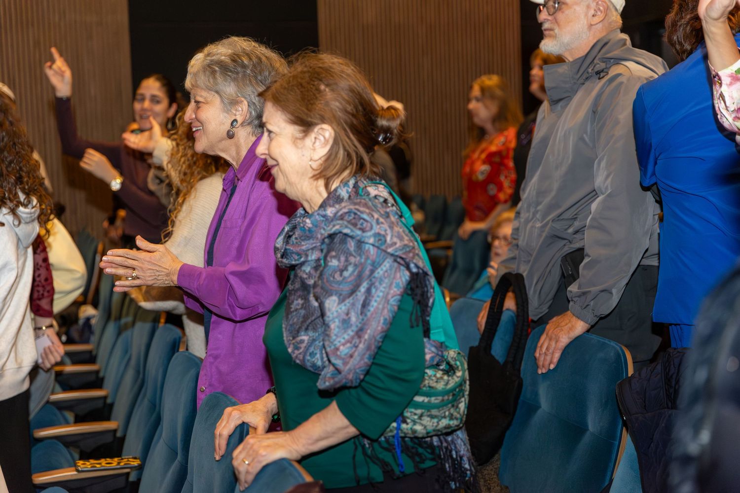 Audience members react with enthusiasm during indoor event.
