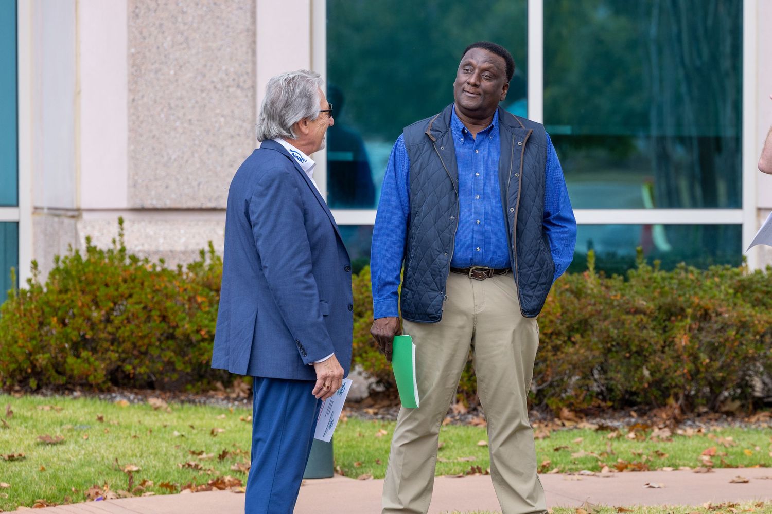 People interact outside modern office building during autumn gathering.