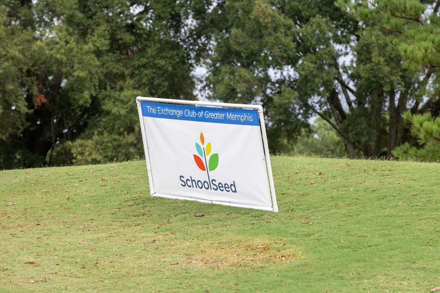 Sponsorship banners displayed on a grassy hill at an outdoor event.