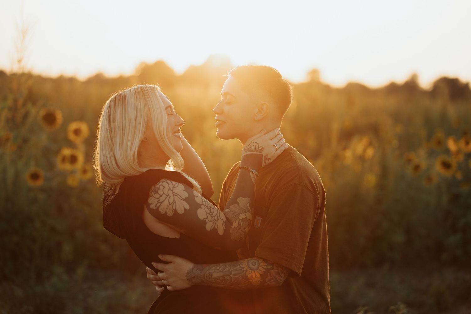 Soft golden light bathes a loving moment in a field of sunflowers at dusk.