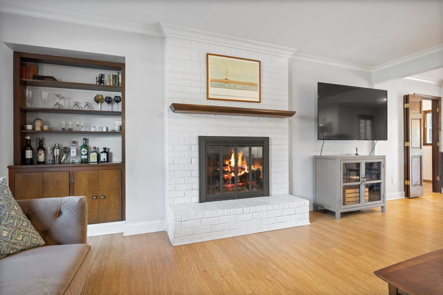 Modern open concept living room with white brick fireplace, hardwood floors, and minimalist decor in a contemporary home.