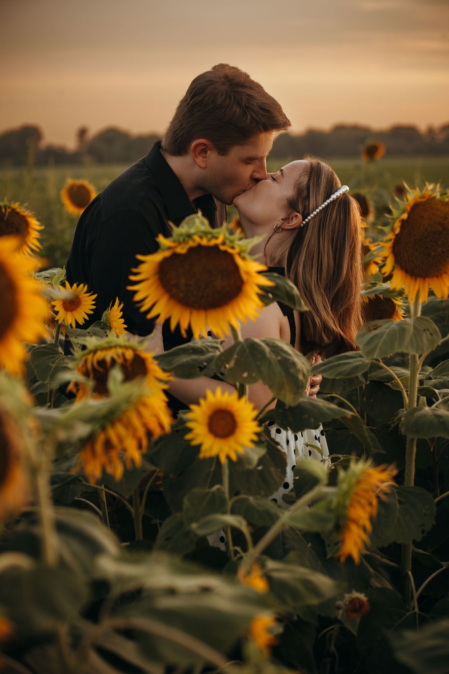 Romantic moment captured in a sunflower field at golden hour.