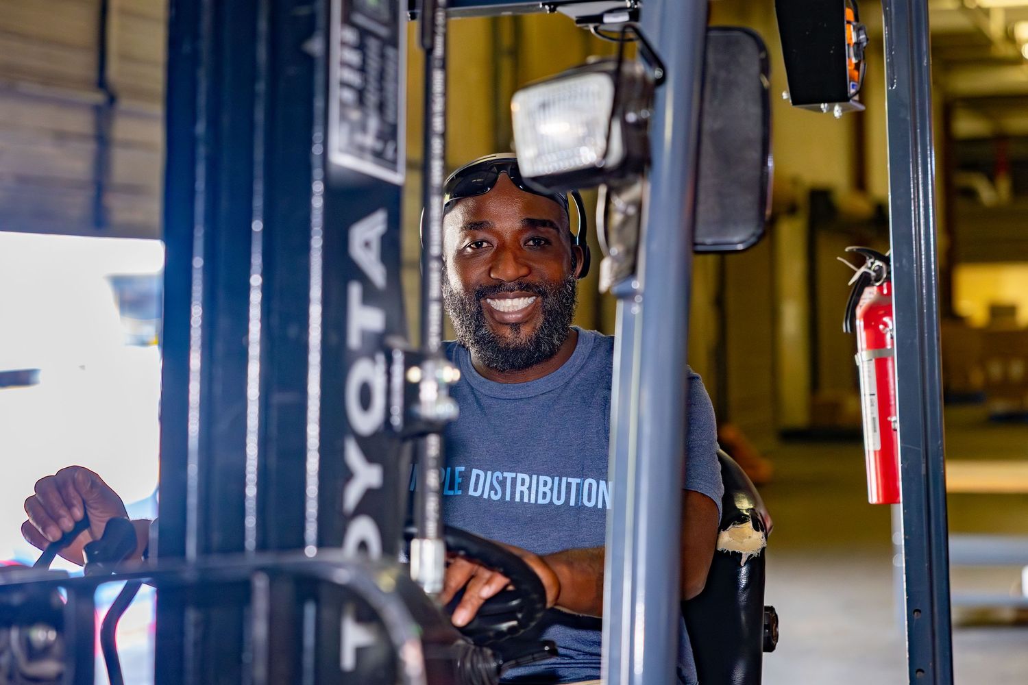 Forklift operator smiling while working in warehouse distribution center.