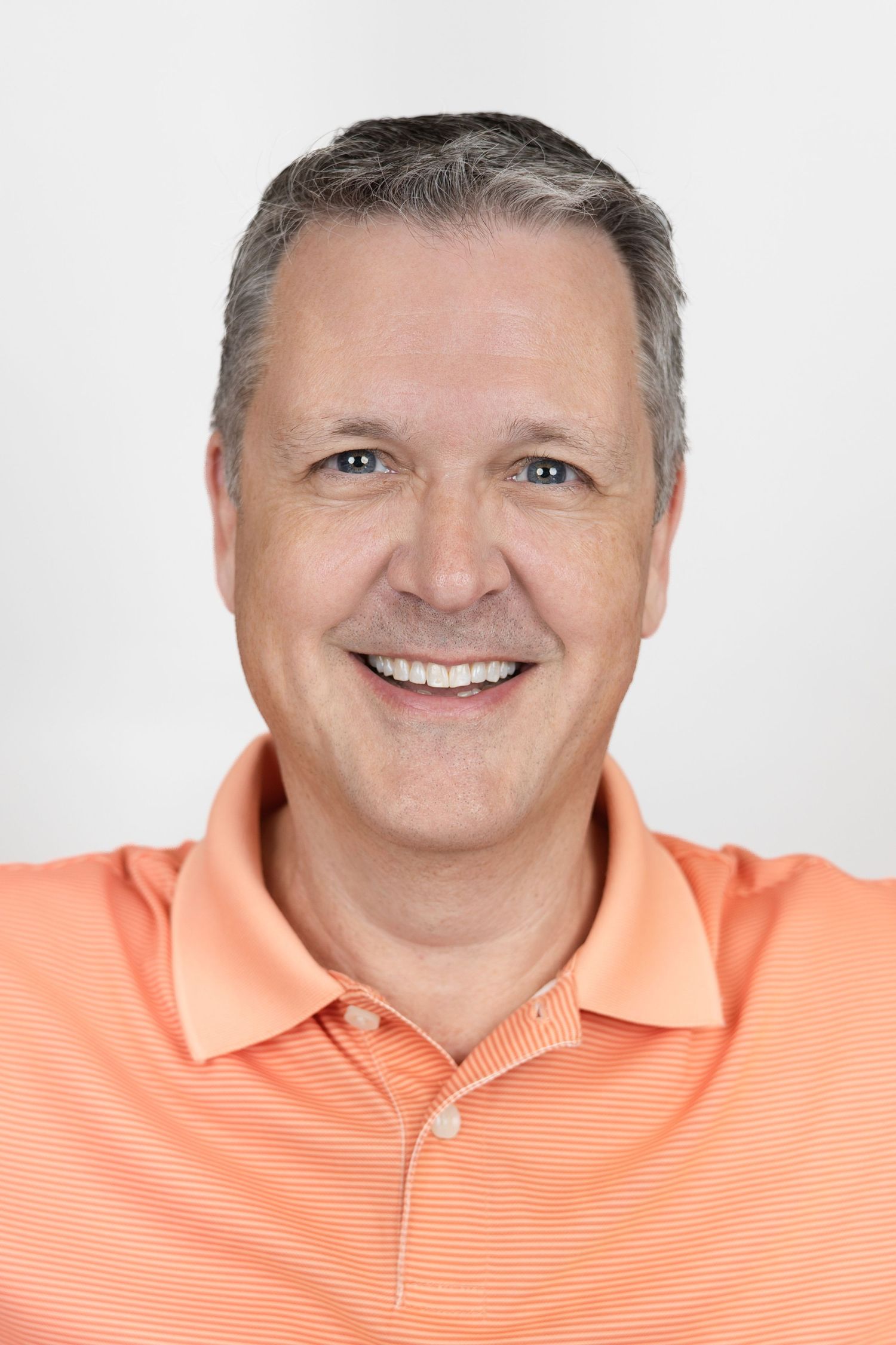 Portrait series in coral polo shirt against white background with friendly expressions.