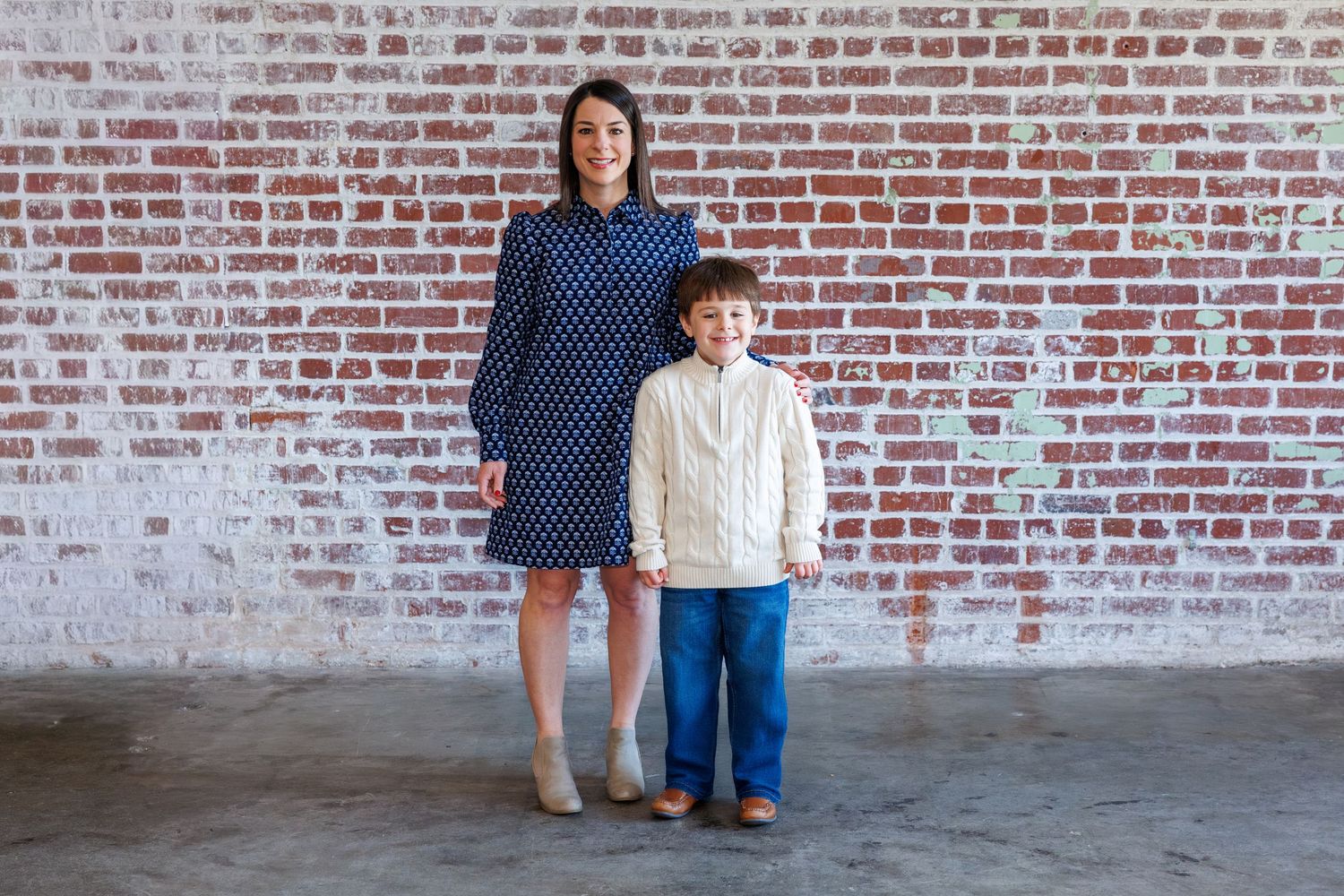 Family members arranged in front of weathered red brick wall.