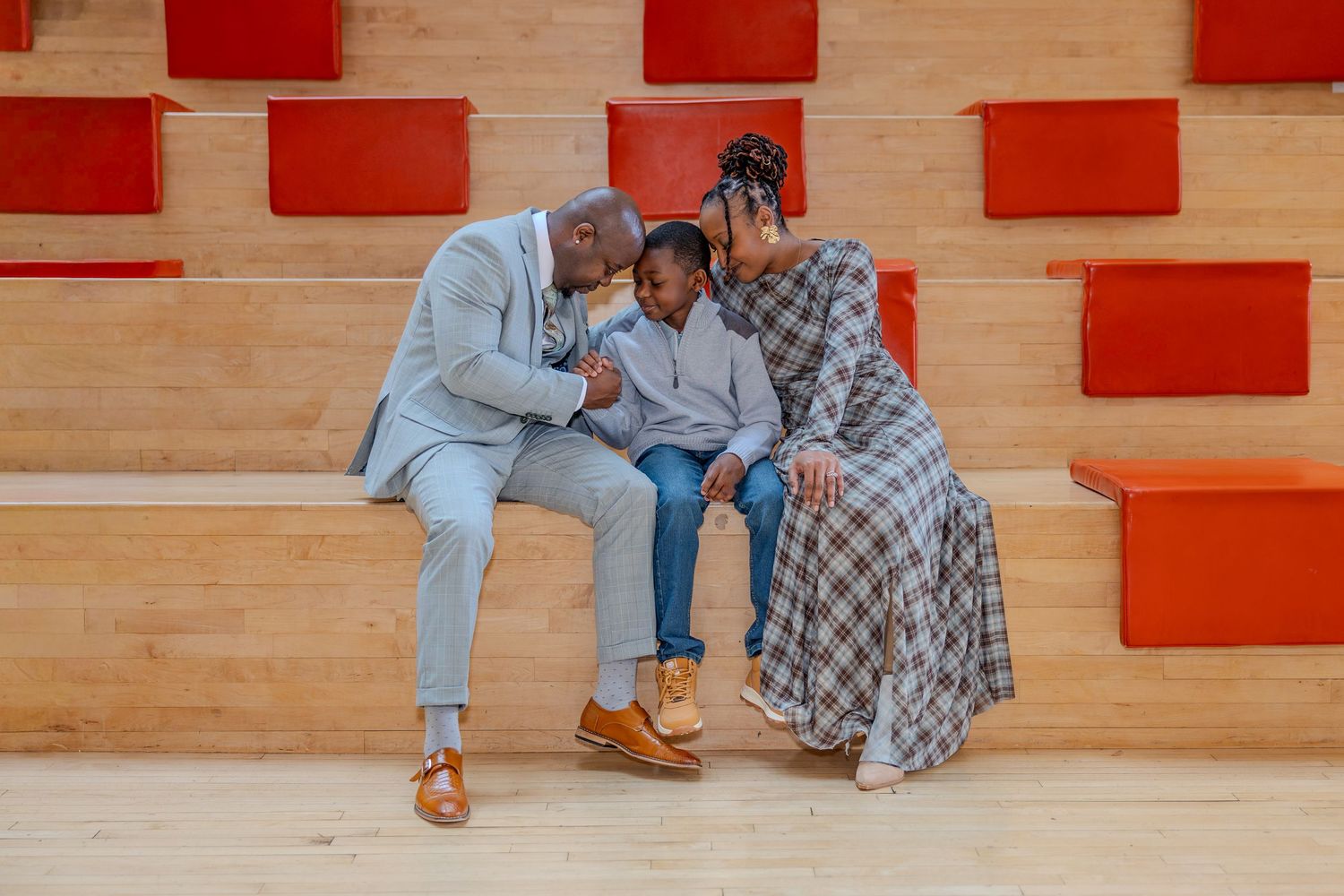 Modern family portrait session on wooden floor with red wall accents.