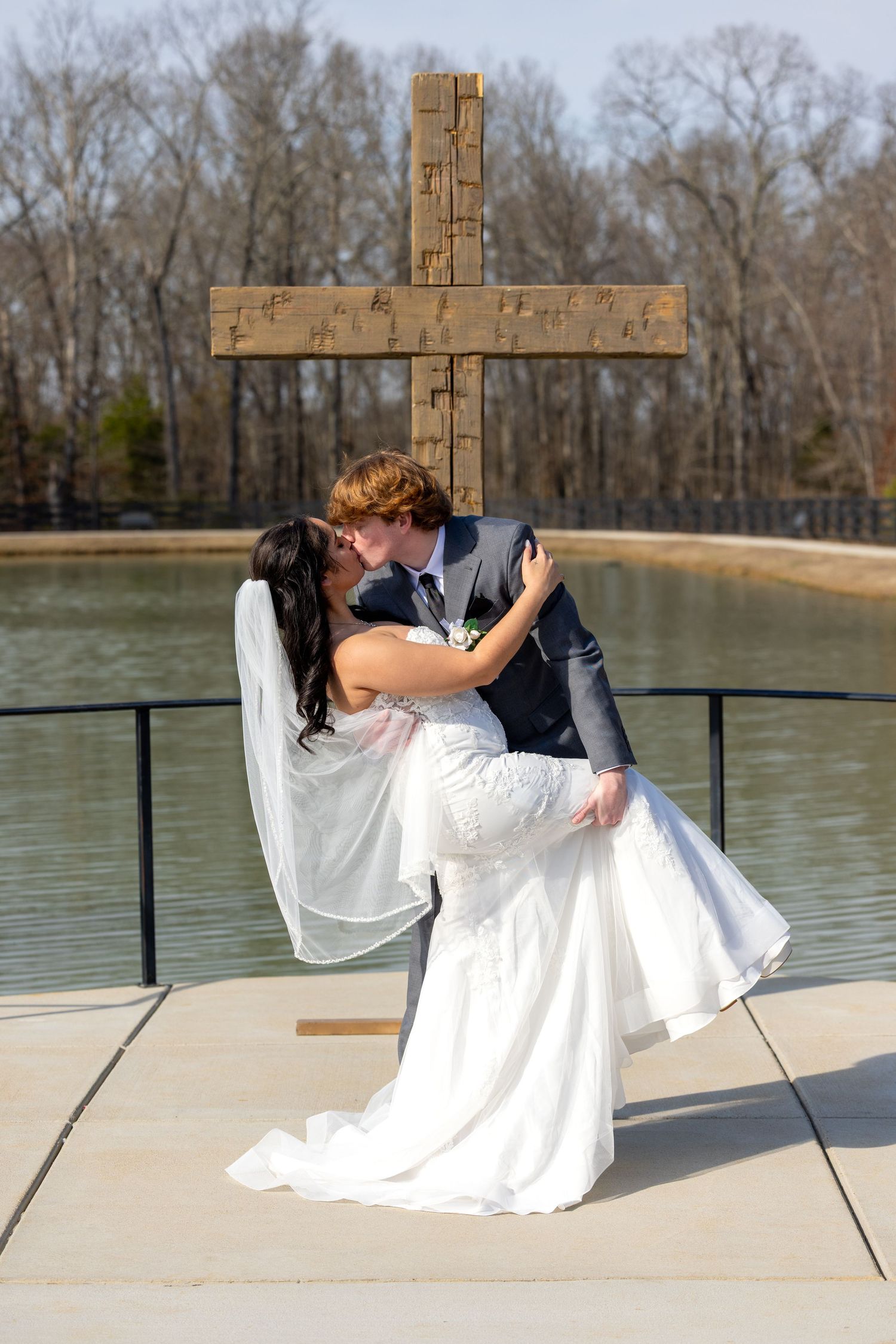 Romantic wedding photo sequence showing a couple dipping and kissing by a lake with a wooden cross in the background.