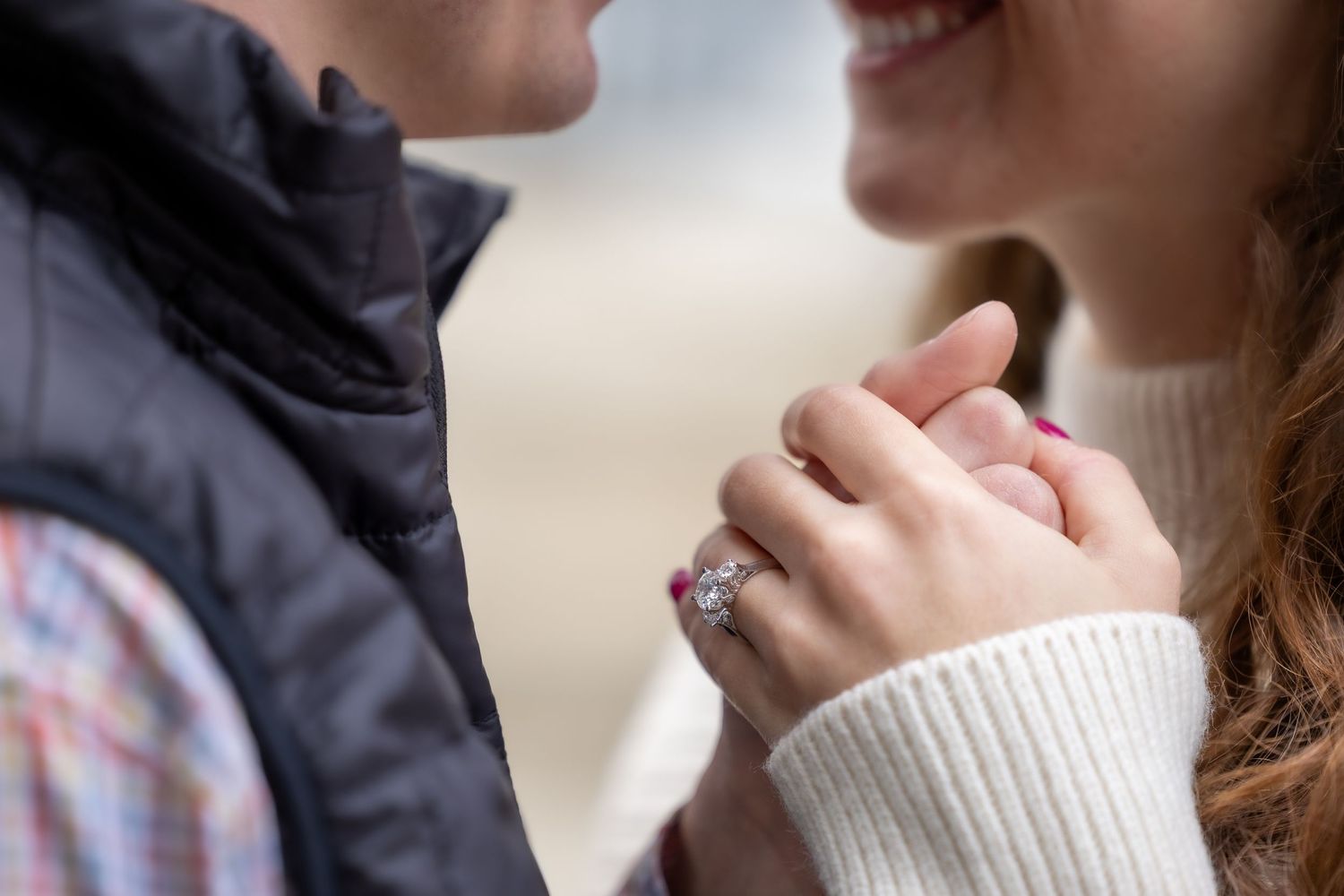 Close up shot of someone holding a white coffee mug in their hands wearing a cream colored sweater.