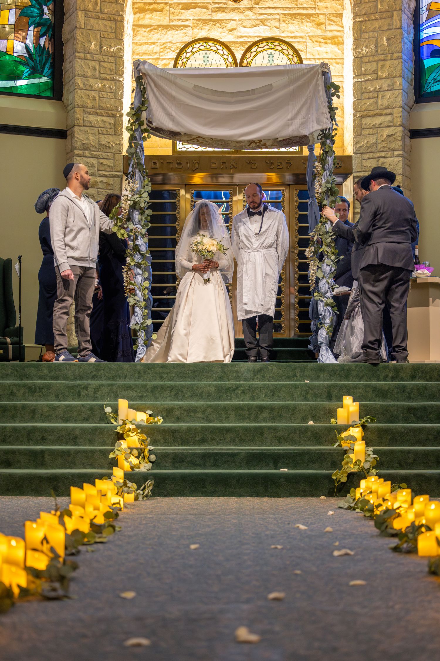 Wedding ceremony altar decorated with white draping and yellow floral arrangements.