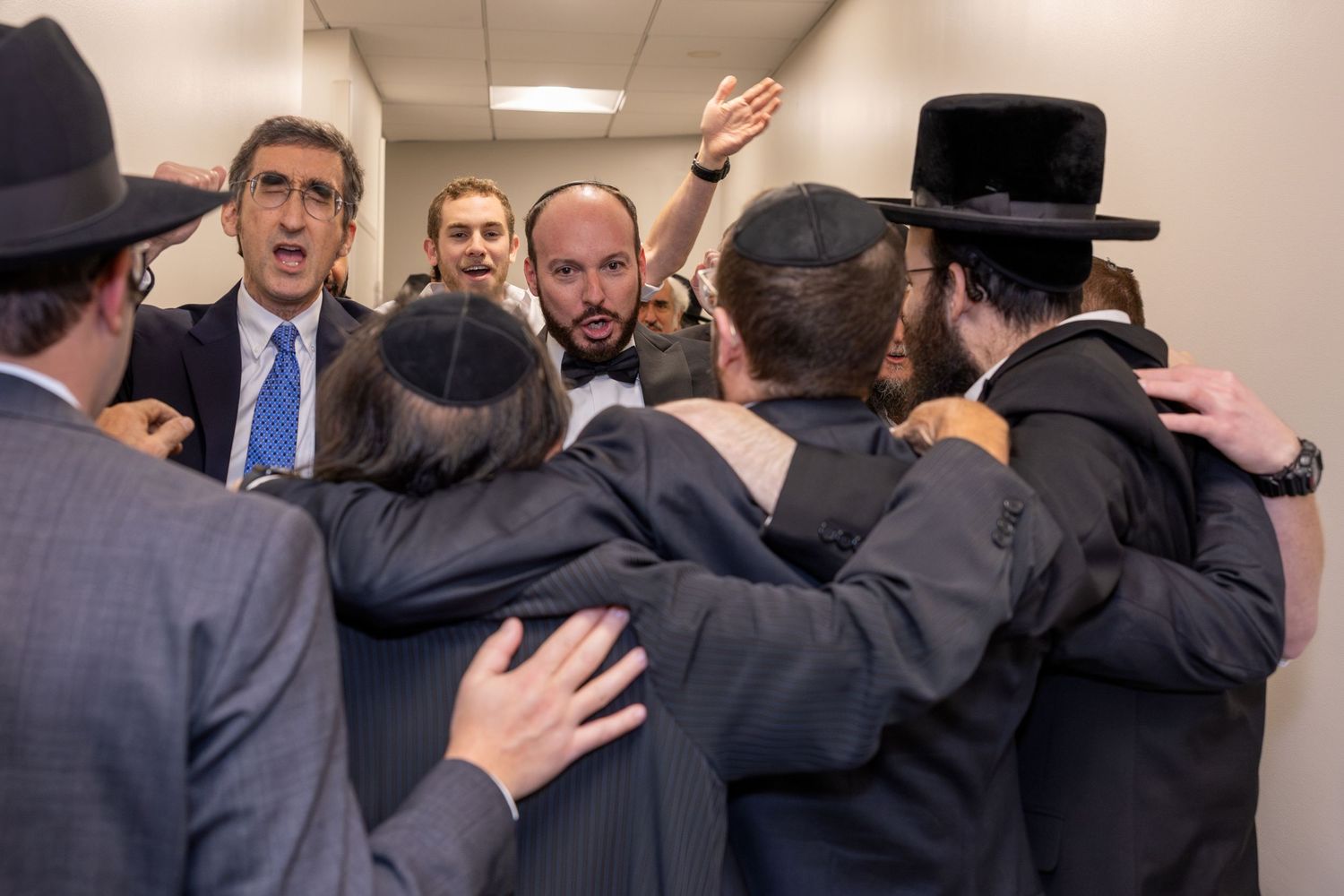 Group of people embracing in celebration at indoor gathering.