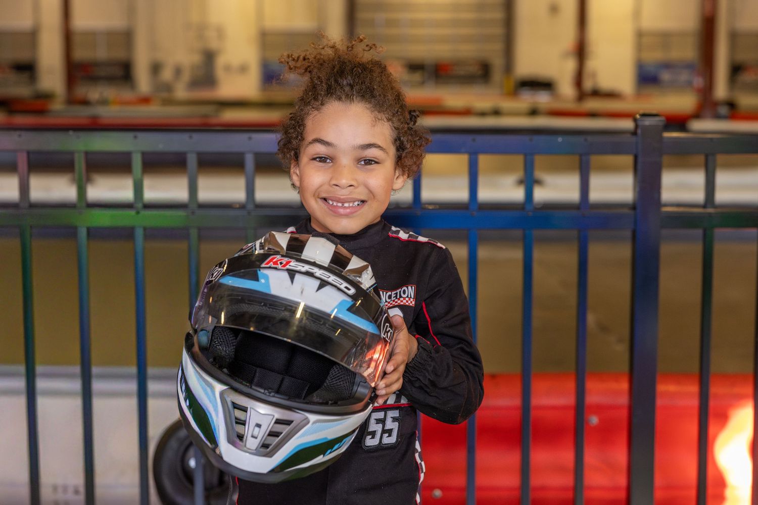 Young racer holding a white racing helmet with enthusiasm.