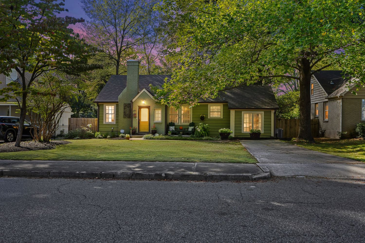 Charming craftsman style home with illuminated windows and landscaping at twilight.