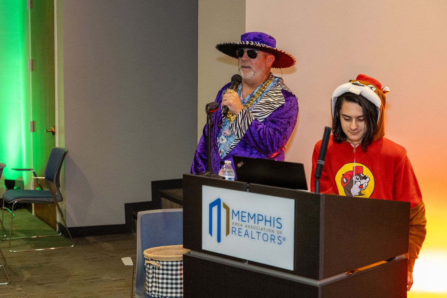 Costumed attendees at a convention with colorful decorations and Memphis branding visible.