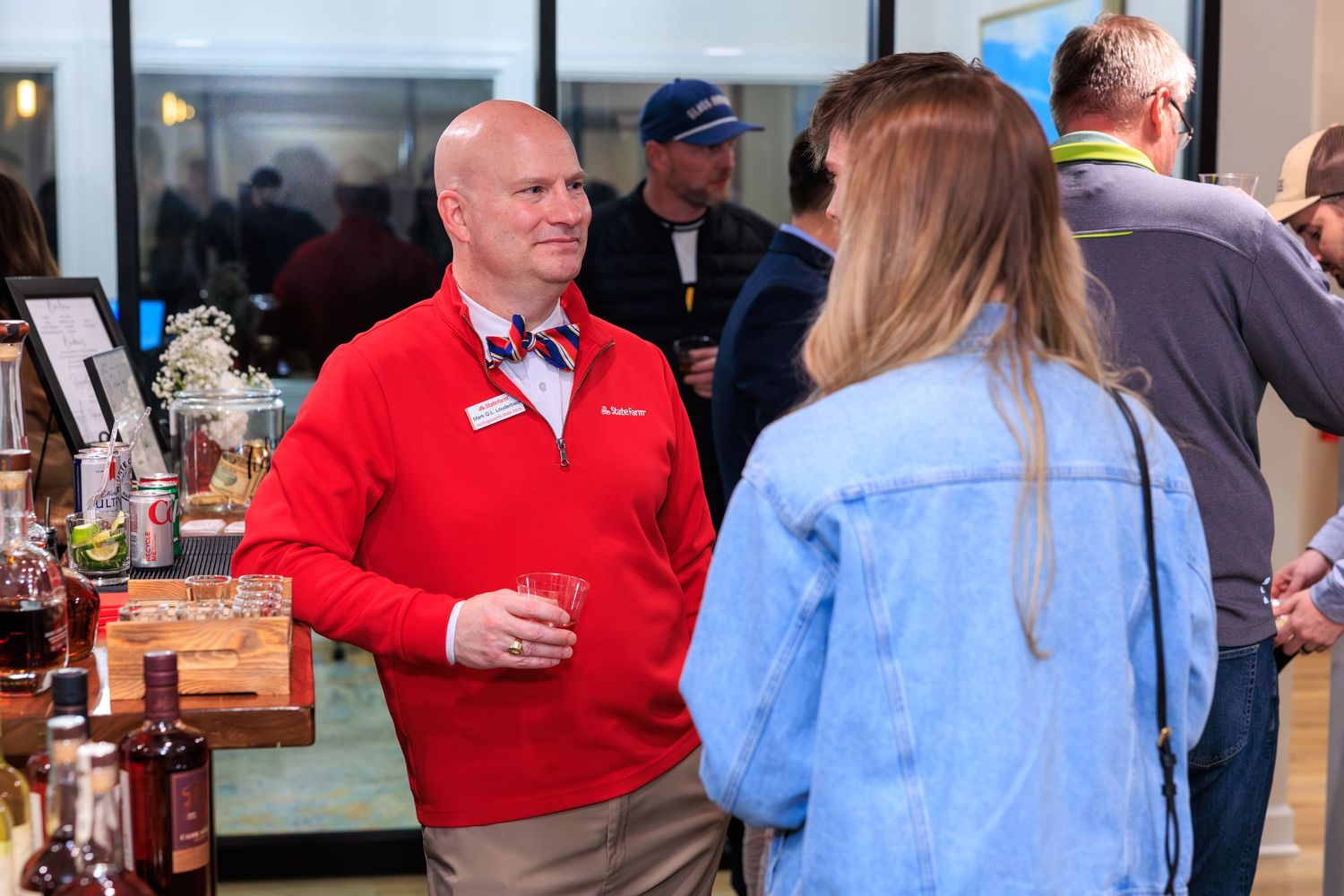 People in red and blue shirts having animated conversations at what appears to be a social gathering or event.