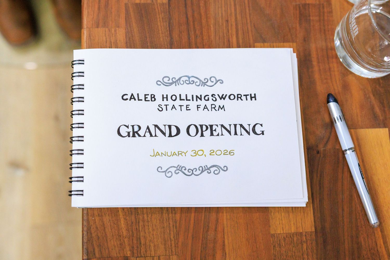 Guest signing book at a grand opening event with elegant calligraphy and spiral binding on wooden surface.