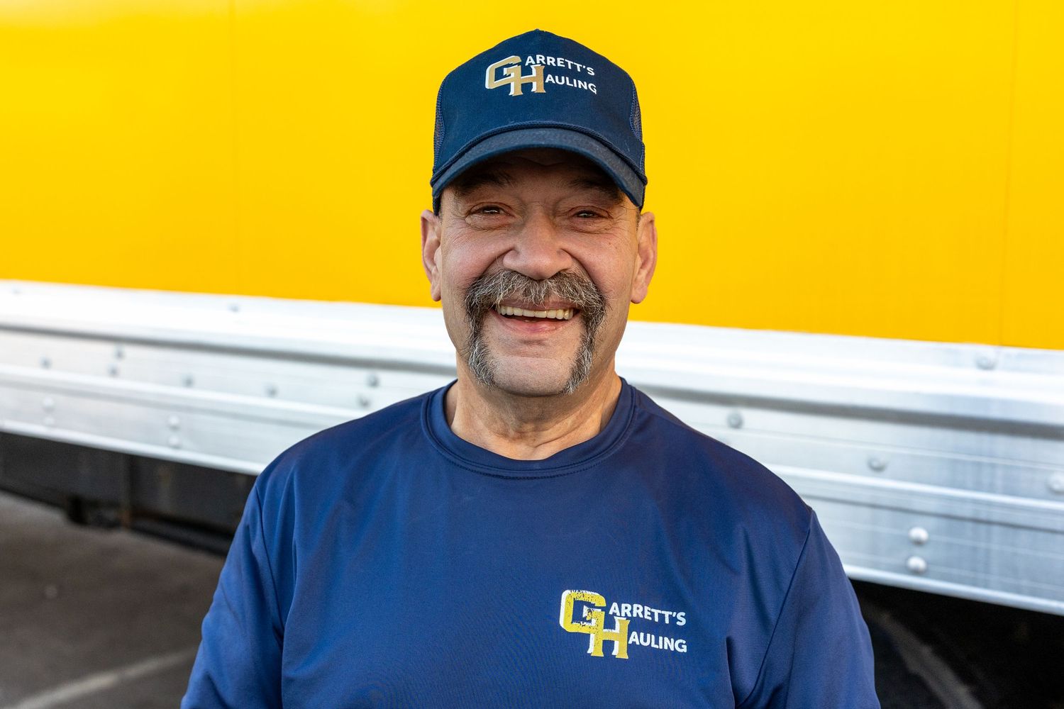 Professional team member in navy blue uniform and cap against bright yellow background.
