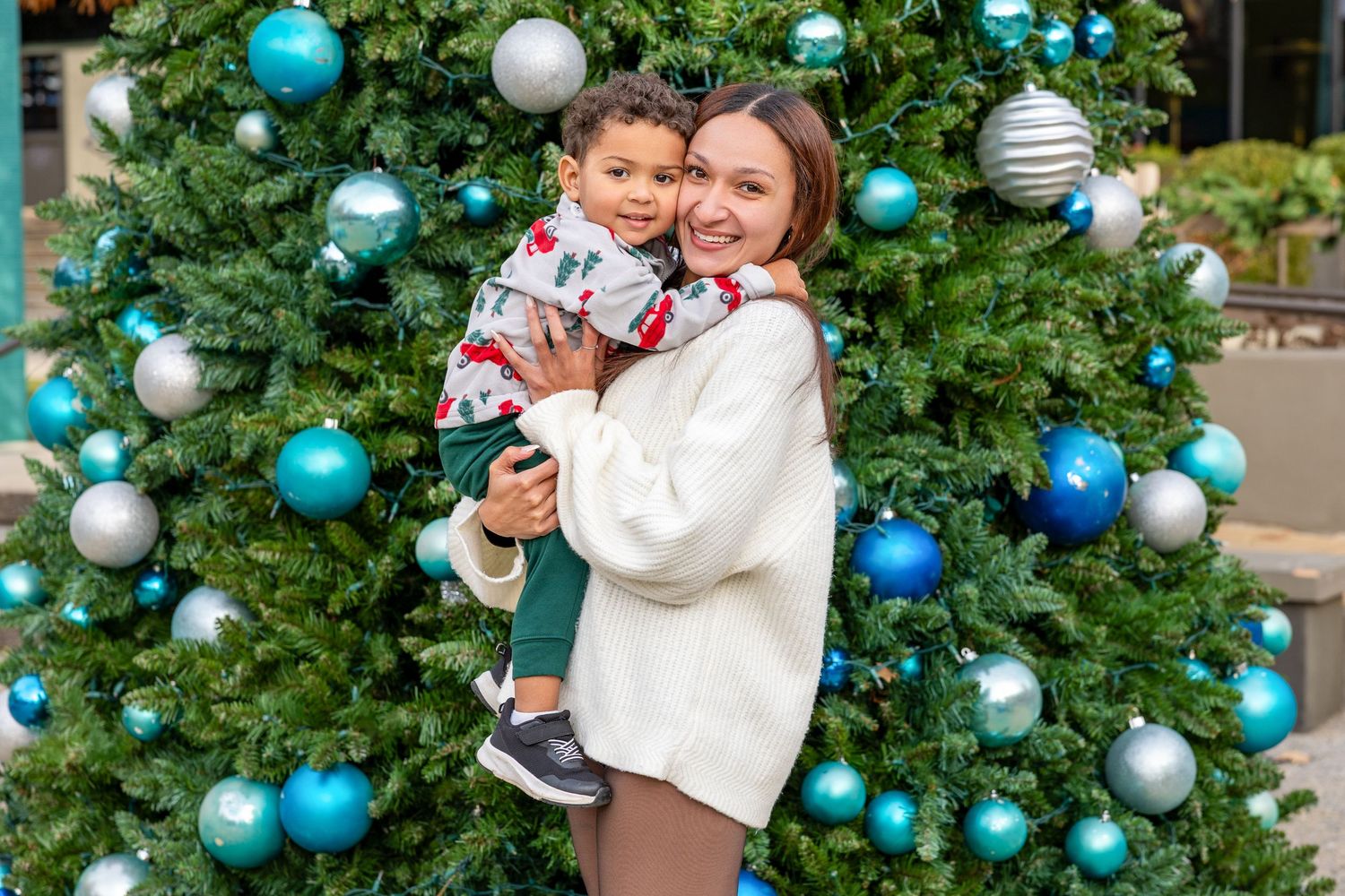 Festive Christmas tree decorated with blue and silver ornaments in an outdoor setting.