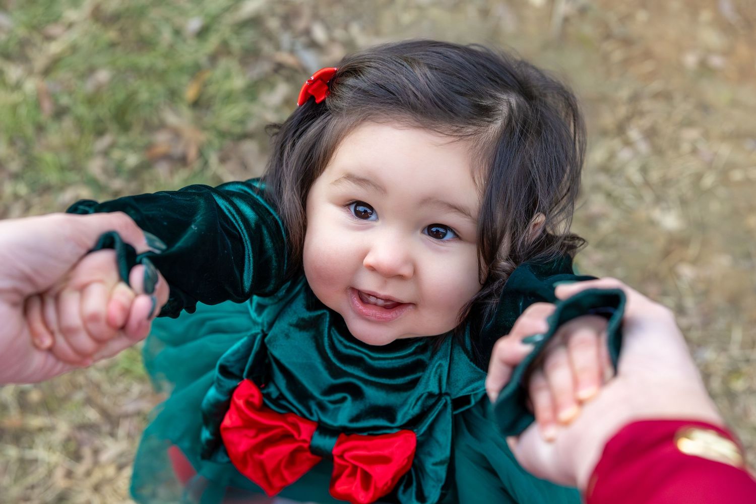 Playful family photos with child wearing festive red and green holiday outfit.