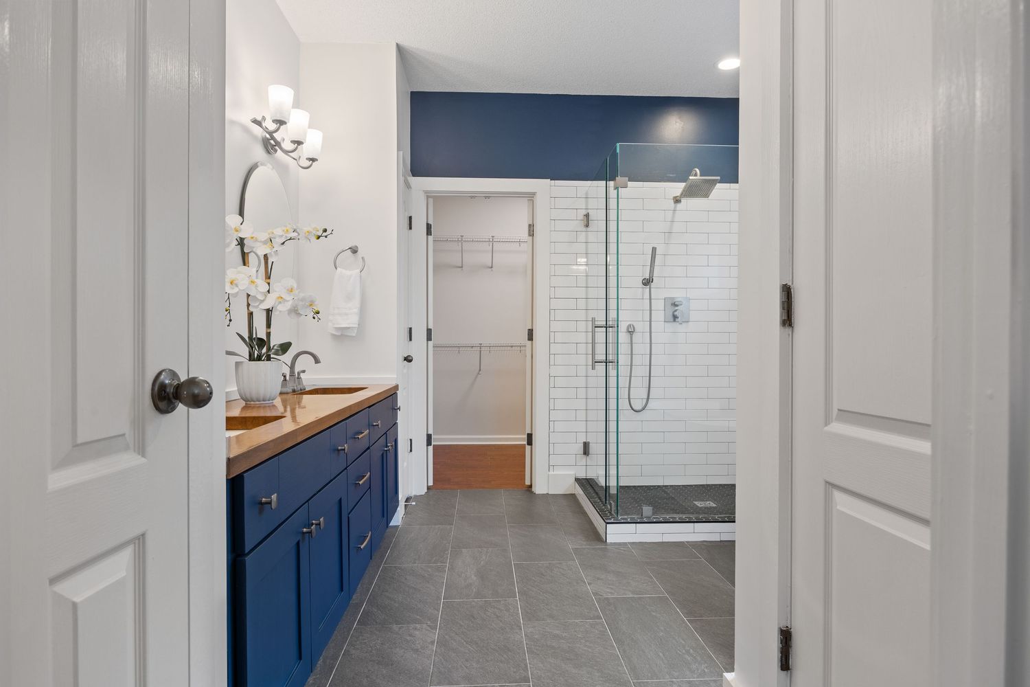 Modern white hallway with paneled walls and doors featuring blue accent walls and contemporary light fixtures.