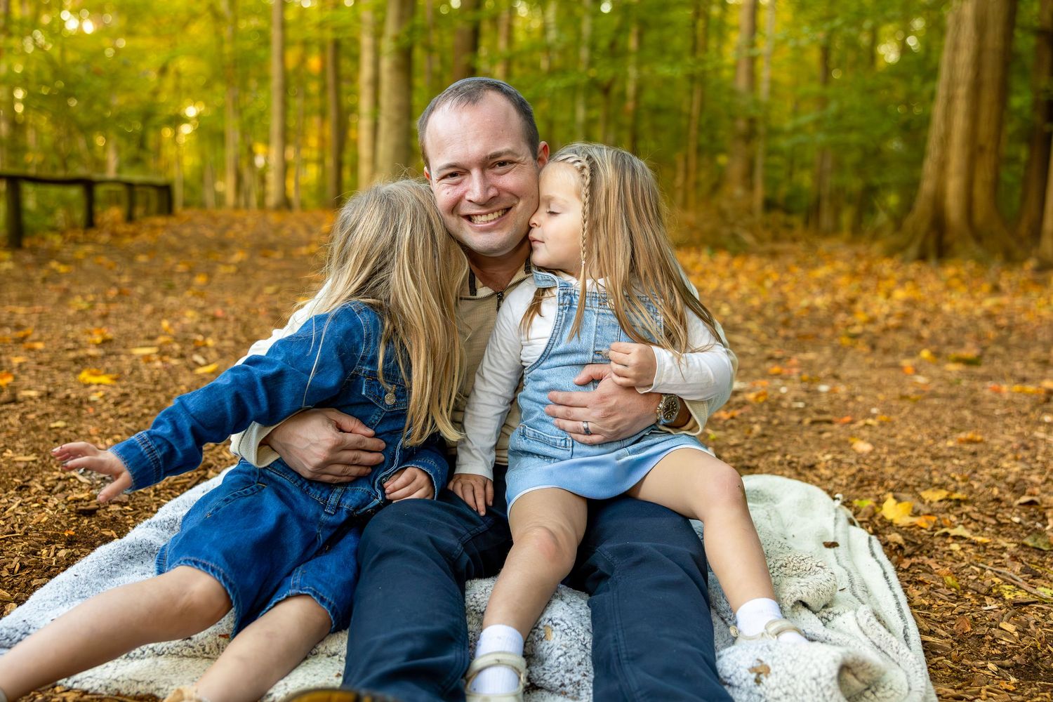 Outdoor family portrait session among fall trees and leaves.