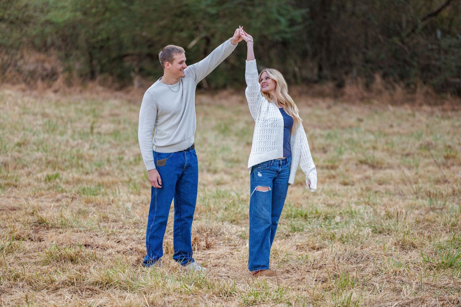 A couple walking together through a grassy field on an autumn day.