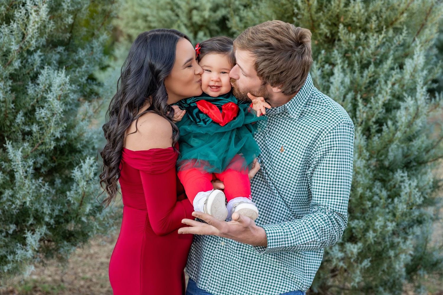 Joyful family moment captured during outdoor photo session with evergreen backdrop.
