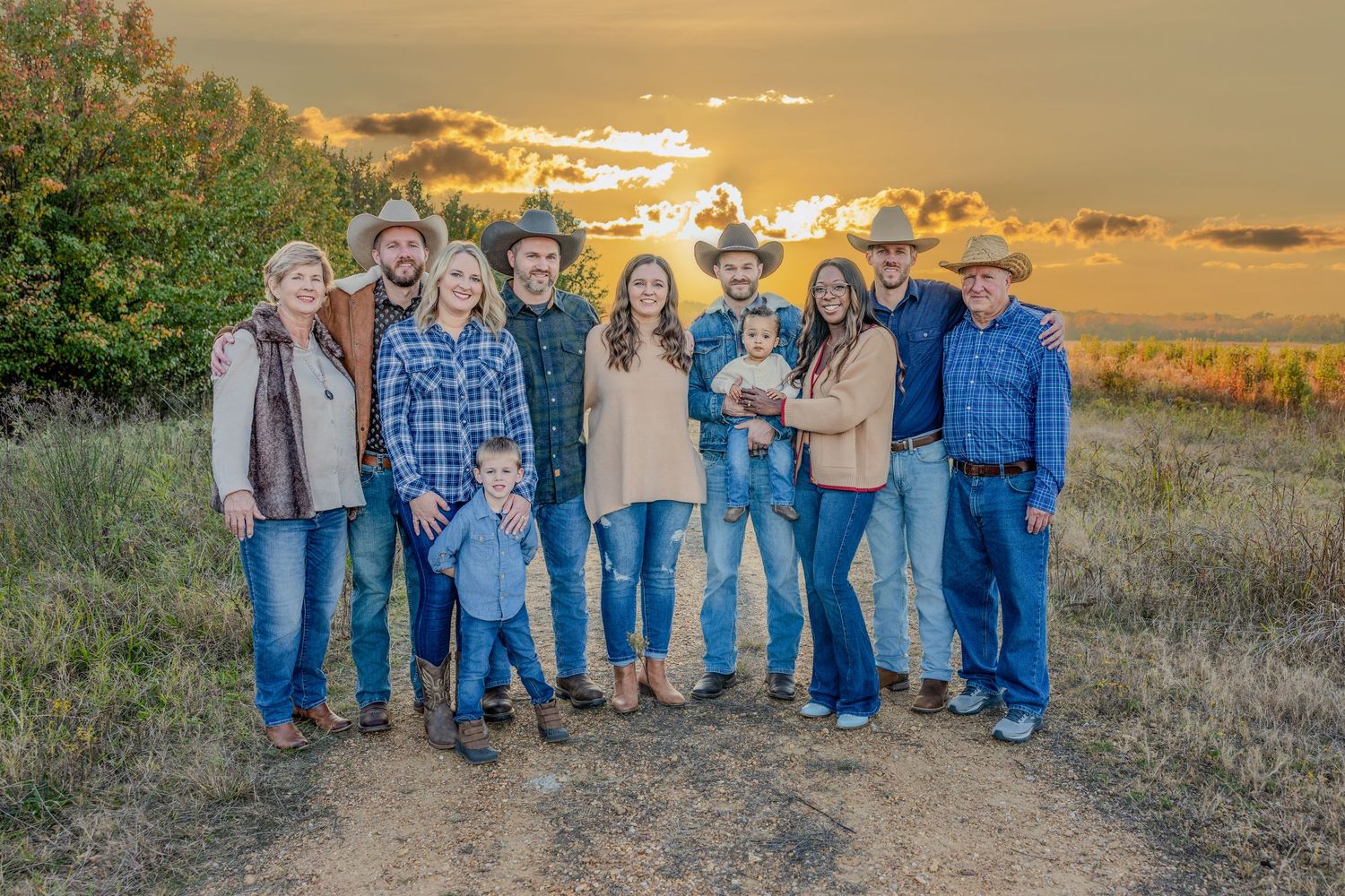 Large family group portrait at sunset in a grassy field wearing denim and casual clothing.