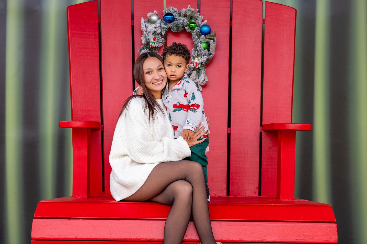 Large red Adirondack chair decorated with holiday greenery and bows.