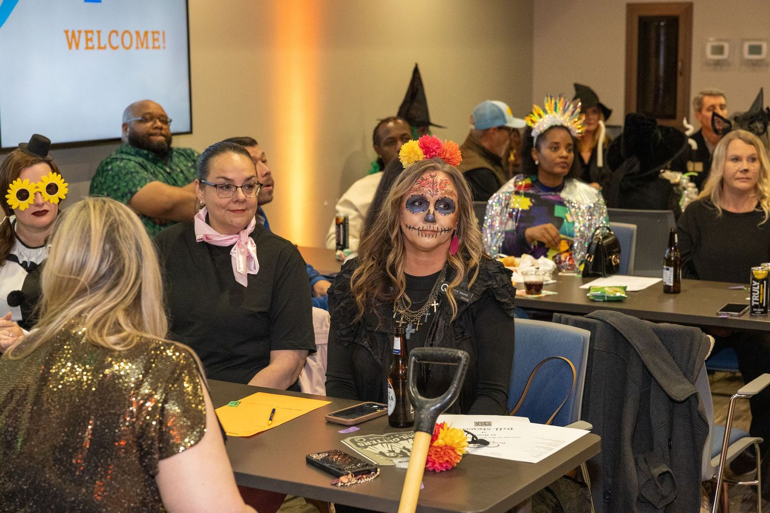 Conference room filled with costumed attendees and Halloween decorations.