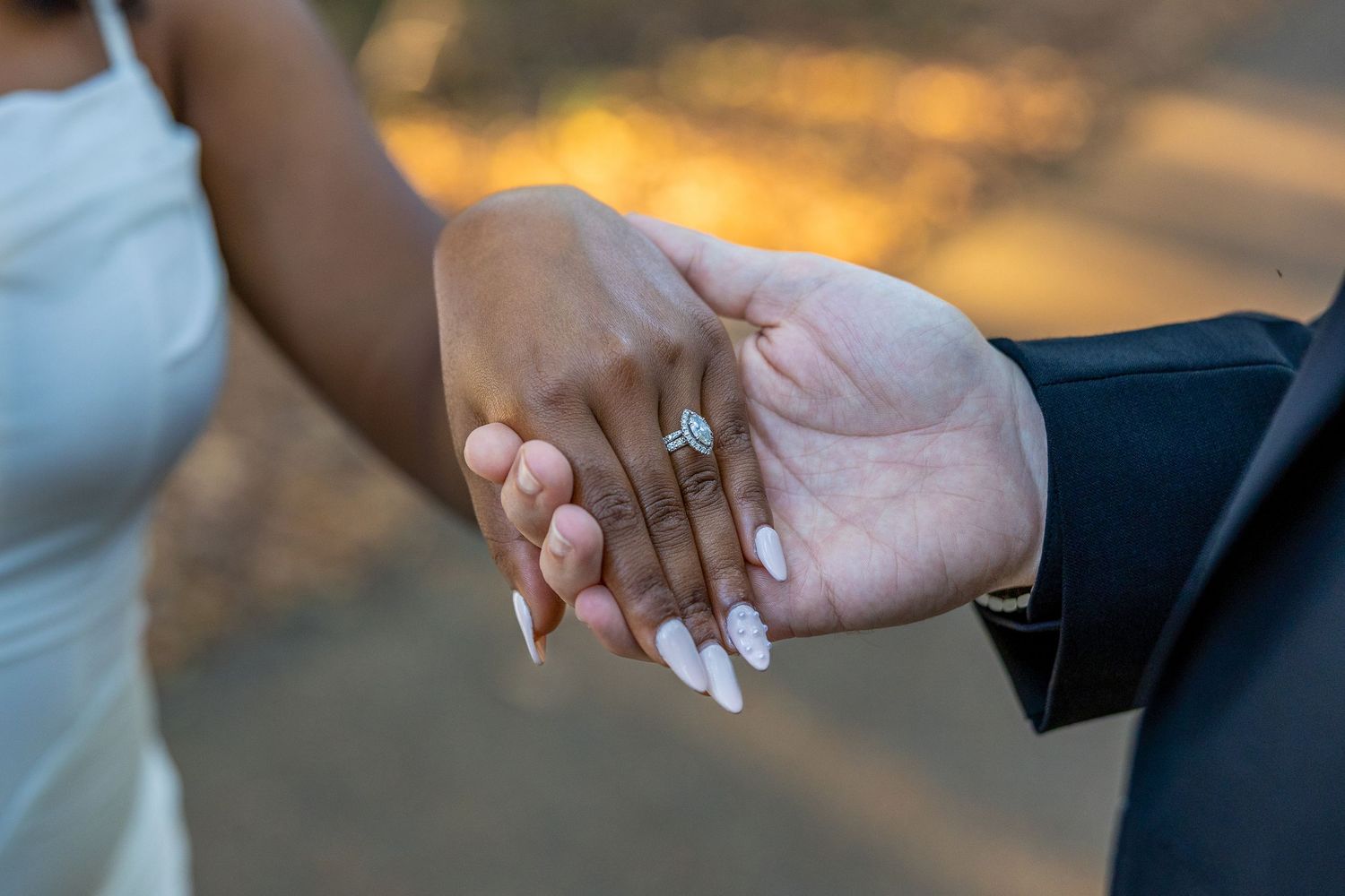 Close-up shot of hands holding and walking together on a wooded path.