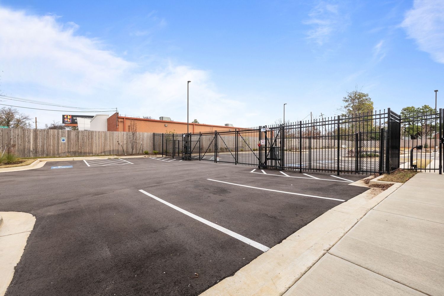Large paved parking area with new line markings and metal railings under blue sky.