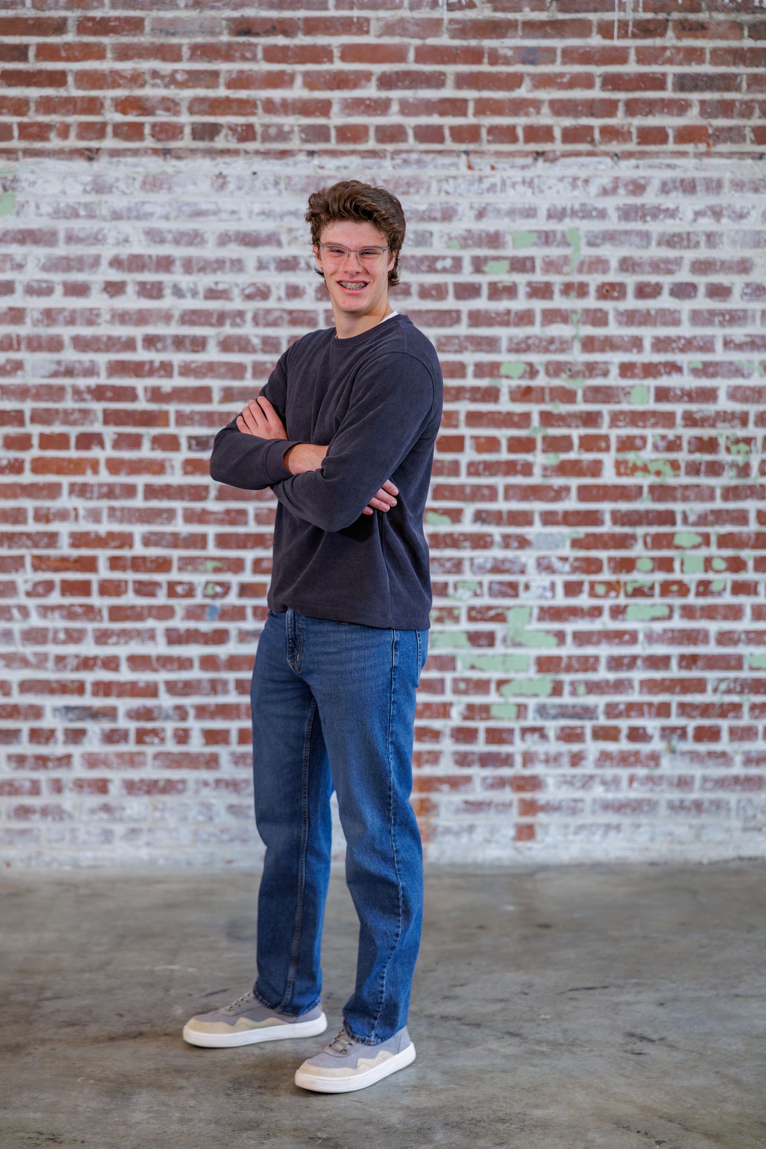 Person in casual attire leaning against a brick wall in various poses.