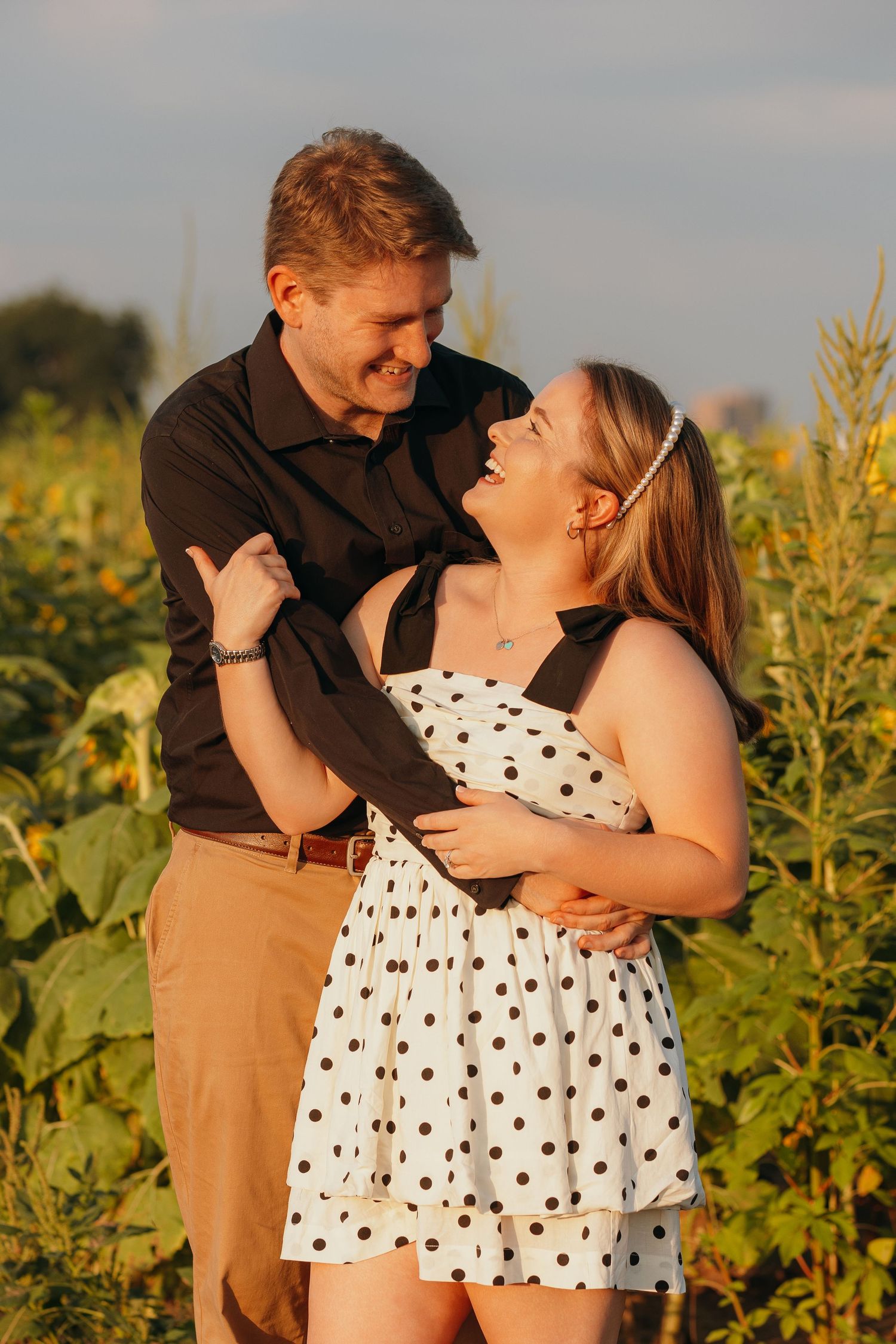 Romantic embrace in a sunflower field during sunset.