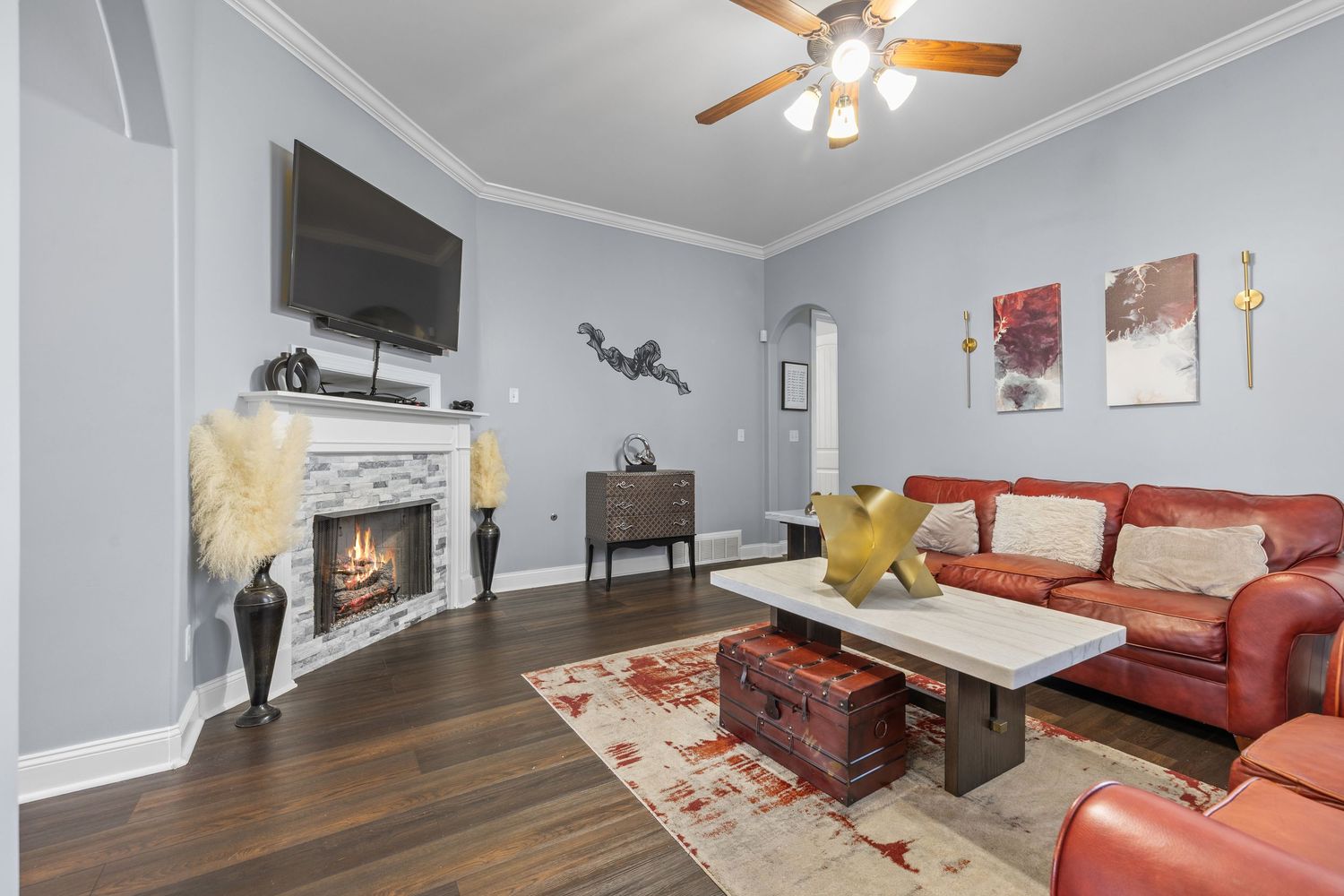 Spacious living room with red sofa, ceiling fan, and modern decor.